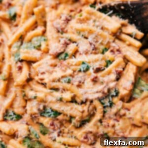 A bowl of Marry Me Pasta with chicken, spinach, and sun-dried tomatoes, topped with Parmesan.