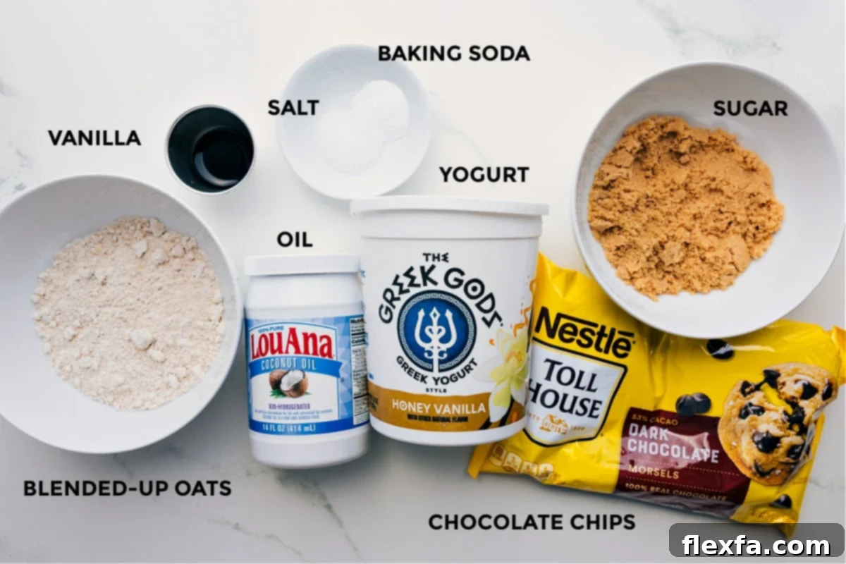 Carefully prepped ingredients for making healthy brownies, including blended oat flour, rich dark chocolate chips, creamy Greek yogurt, coconut oil, vanilla extract, salt, baking soda, and coconut sugar.