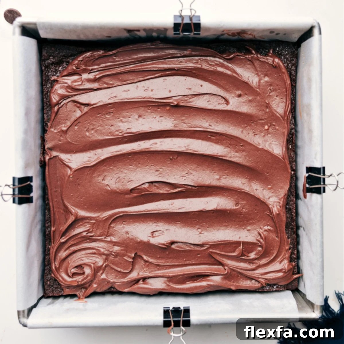 Deliciously thick chocolate frosting generously spread over the cooled healthy brownies, creating an irresistible top layer.