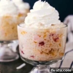 A serving of Frog Eye Salad topped with miniature marshmallows and shredded coconut, ready to enjoy.