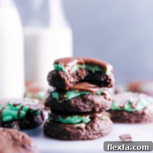 A perfectly baked Mint Brownie Cookie, frosted with green peppermint cream cheese frosting and drizzled with chocolate ganache.