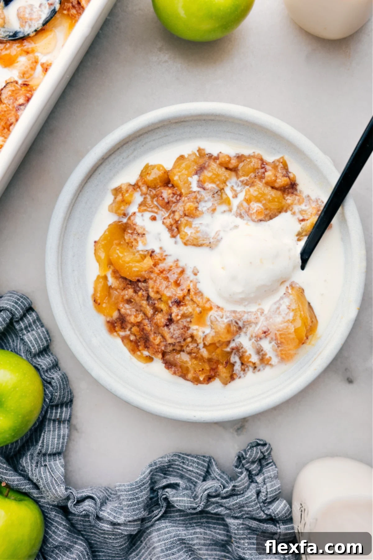 The Best Apple Dump Cake With Ice Cream A slice of warm Apple Dump Cake, topped with a scoop of melting vanilla ice cream, served on a white plate.