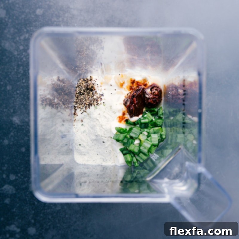 Overhead image of all the fresh ingredients for Chipotle Ranch Dip neatly arranged in a blender, ready to be processed into a creamy dip.