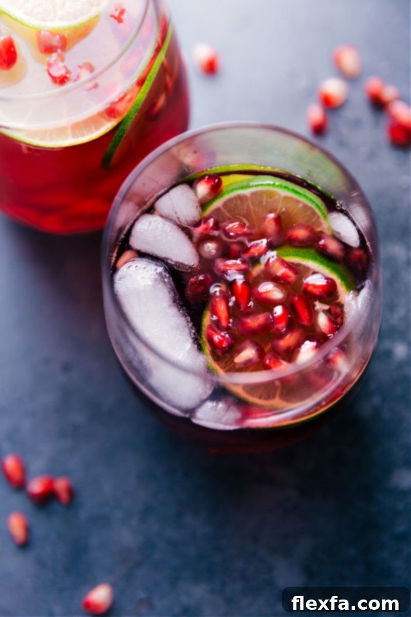A glass of Sparkling Pomegranate Juice with fresh pomegranate seeds and lime slices, ready to be enjoyed.