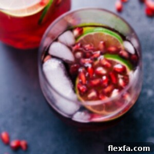 Sparkling Pomegranate Juice in a clear glass with ice, lime, and pomegranate seeds.