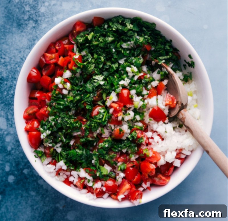 Overhead image of freshly prepared Pico de Gallo being gently tossed together in a large glass bowl, highlighting the colorful medley of diced vegetables.