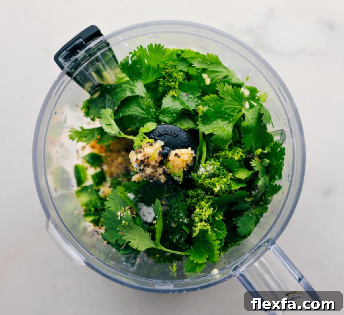 All the ingredients in the cilantro lime sauce being added to a food processor.