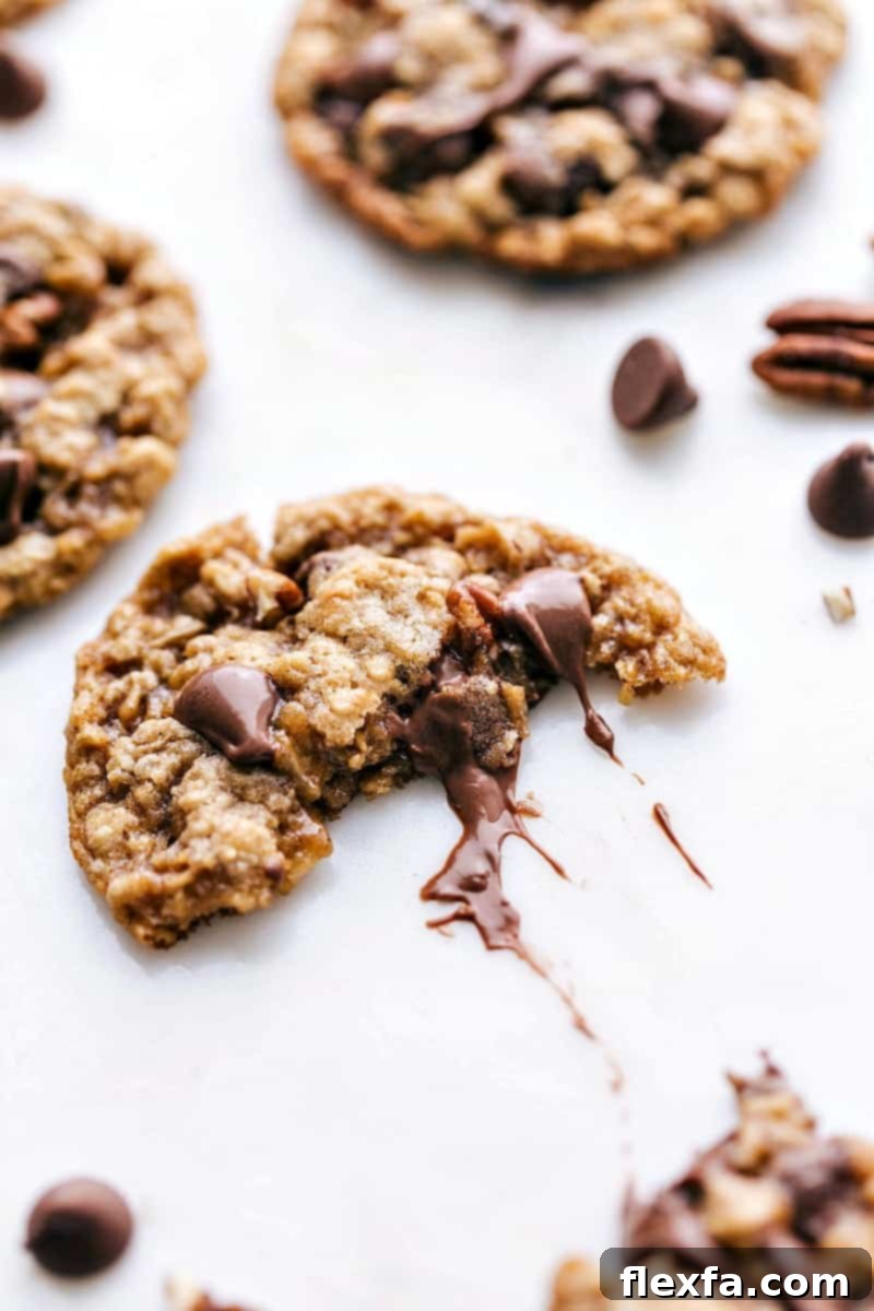 Oatmeal Chocolate Chip Pecan Cookies - Gooey Chocolate Center Revealed A freshly baked oatmeal chocolate chip pecan cookie, expertly split in half, beautifully revealing its warm, gooey chocolate center and embedded pecan pieces.