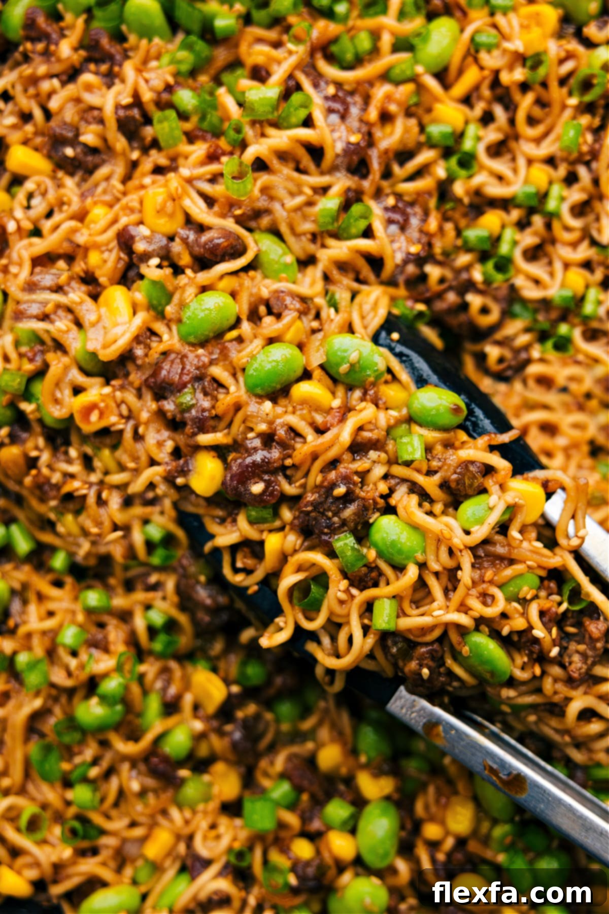 Pork Ramen Stir Fry being picked up with tongs ready to be served and enjoyed, showcasing delicious noodles and vibrant vegetables.