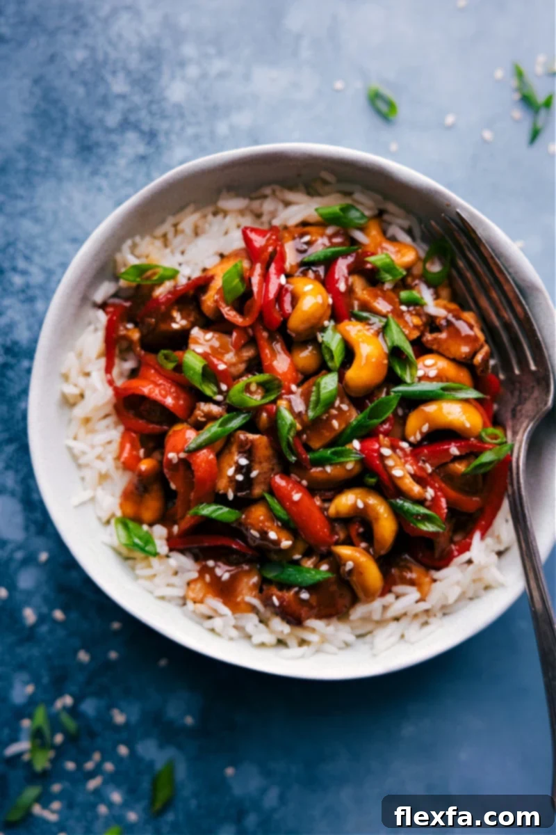 A vibrant bowl of Cashew Chicken topped with fresh green onions and toasted sesame seeds, ready to be served.