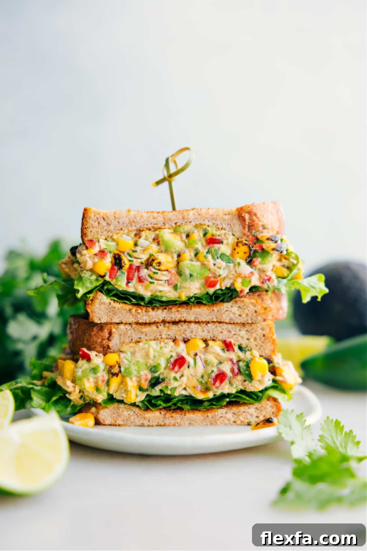 Mexican Street Corn Chicken Salad sandwiched between bread and lettuce, showcasing its vibrant ingredients.