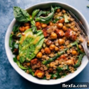 A vibrant Nourish Bowl featuring roasted sweet potatoes, green beans, chickpeas, fresh spinach, and a delicious sauce.