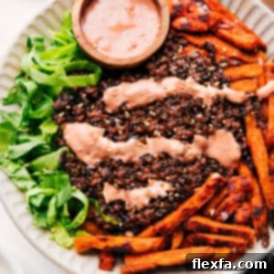 A beautifully assembled Burger Bowl with golden sweet potato fries, seasoned beef, fresh toppings, and a generous drizzle of homemade sauce.
