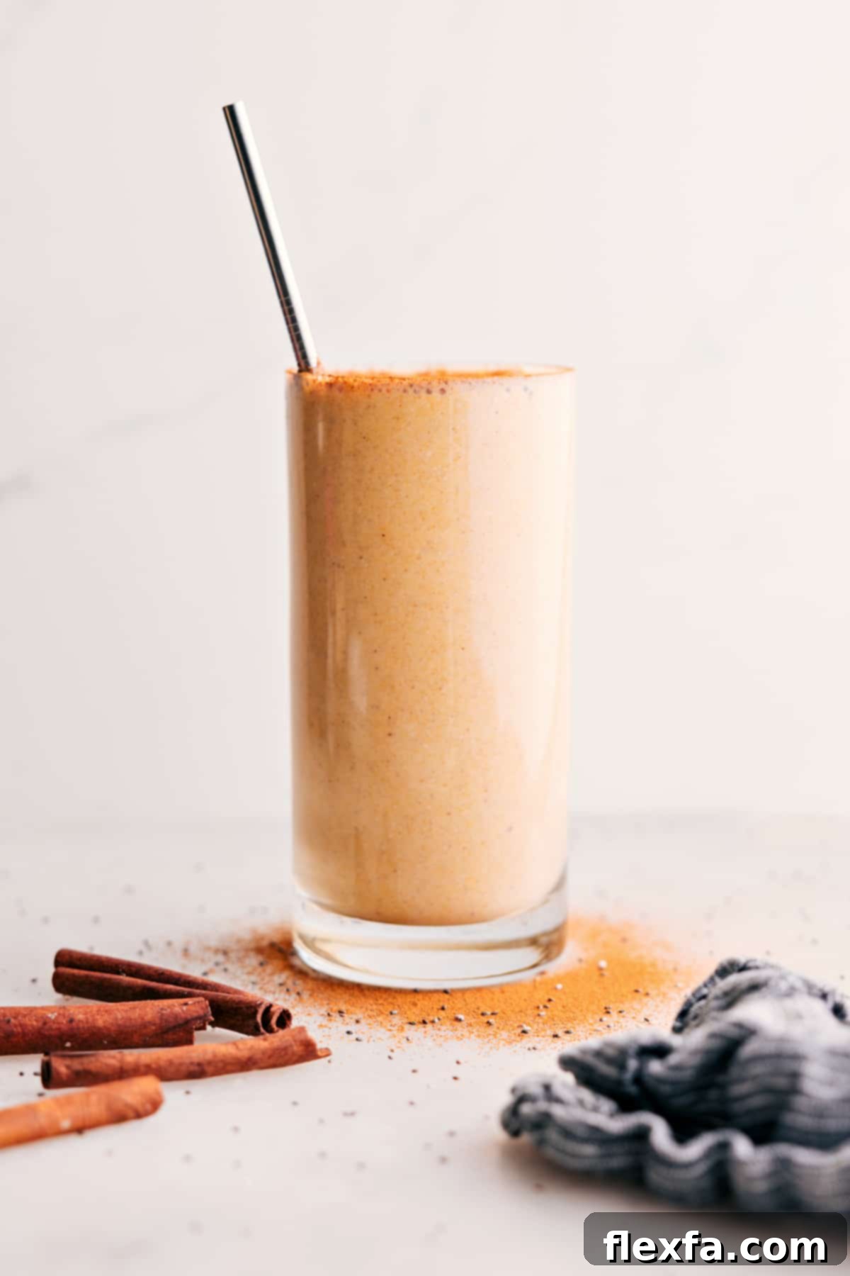 Golden Milk Smoothie: The Ultimate Healthy and Delicious Turmeric Drink A vibrant golden milk smoothie in a glass with a straw, garnished with a sprinkle of cinnamon, set against a bright background.
