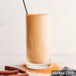 A tall glass of vibrant golden milk smoothie, garnished with a light sprinkle of cinnamon, ready to be enjoyed.