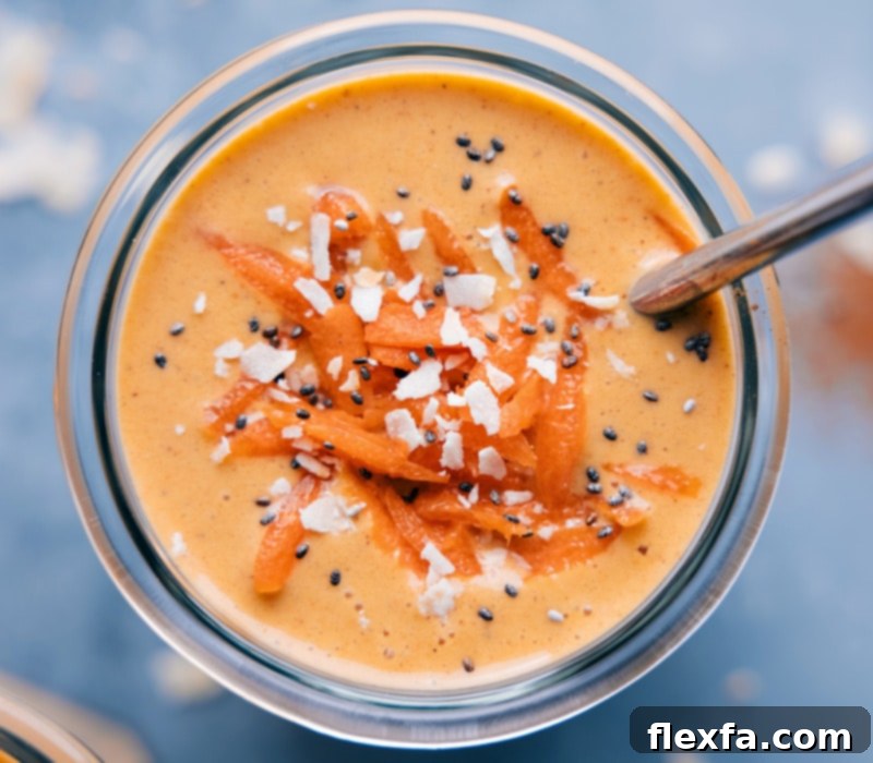 A vibrant orange Carrot Smoothie in a tall glass, garnished with shredded carrots and a hint of spice, ready to be enjoyed as a healthy breakfast or snack.