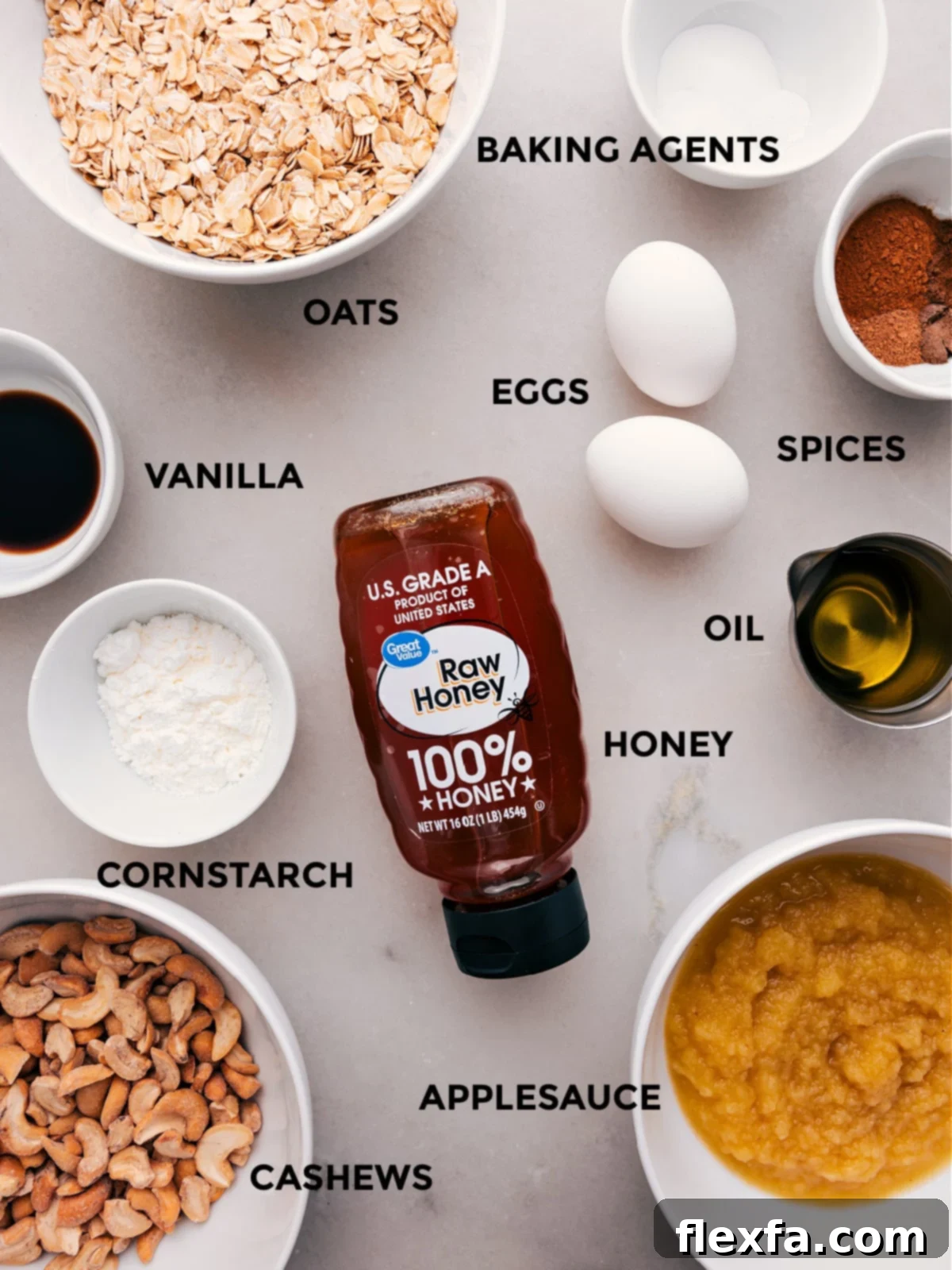 A selection of wholesome ingredients for the healthy apple cake recipe, including old-fashioned oats, cashews, honey, applesauce, coconut oil, eggs, and various warm spices.