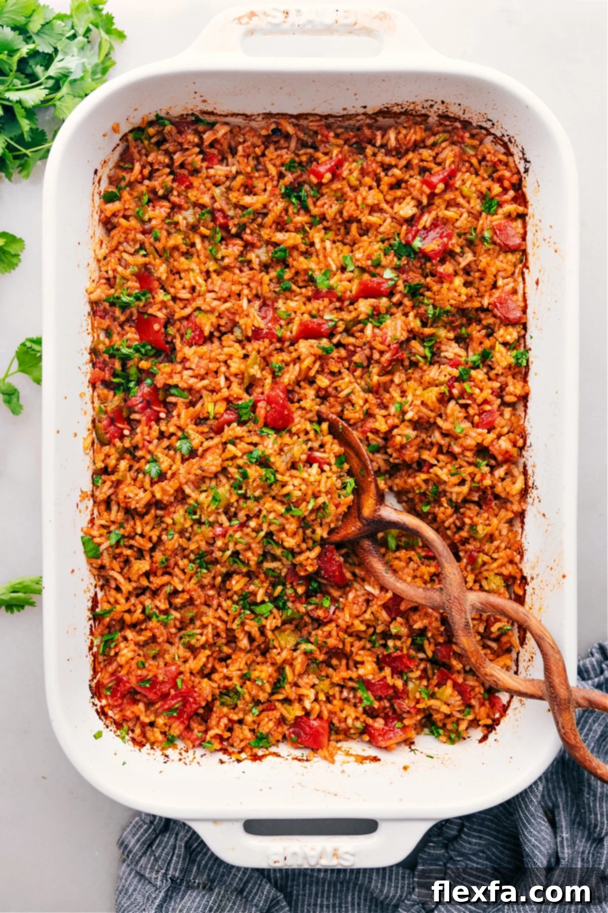 Delicious Baked Mexican Rice Recipe for an Easy Meal A vibrant pan of freshly baked Mexican Rice, garnished with fresh cilantro, ready to be served. The rice appears fluffy and rich in color, indicating deep flavor from the tomatoes and spices, cooked to perfection in a ceramic dish.