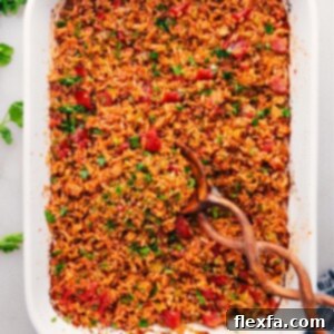 A close-up shot of a perfectly cooked, fluffy Mexican Rice recipe in a baking pan, garnished with fresh cilantro, showcasing its rich reddish-orange color and tender grains.