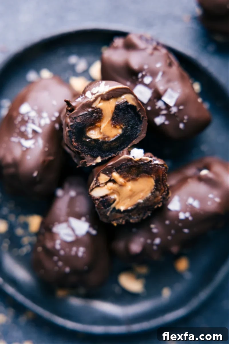 Irresistible Chocolate Covered Dates: A perfect snack, treat, or dessert. Wholesome ingredients cure your sweet tooth without the sugar crash. Recipe by ChelseasMessyApron. #snack #quick #easy #yummy #fresh #cleaneating #healthy #wholefoods #peanutbutter #chocolate #covered #dates A plate showcasing several glistening chocolate-covered dates, with one cut open to reveal the creamy nut butter and chopped nuts filling.