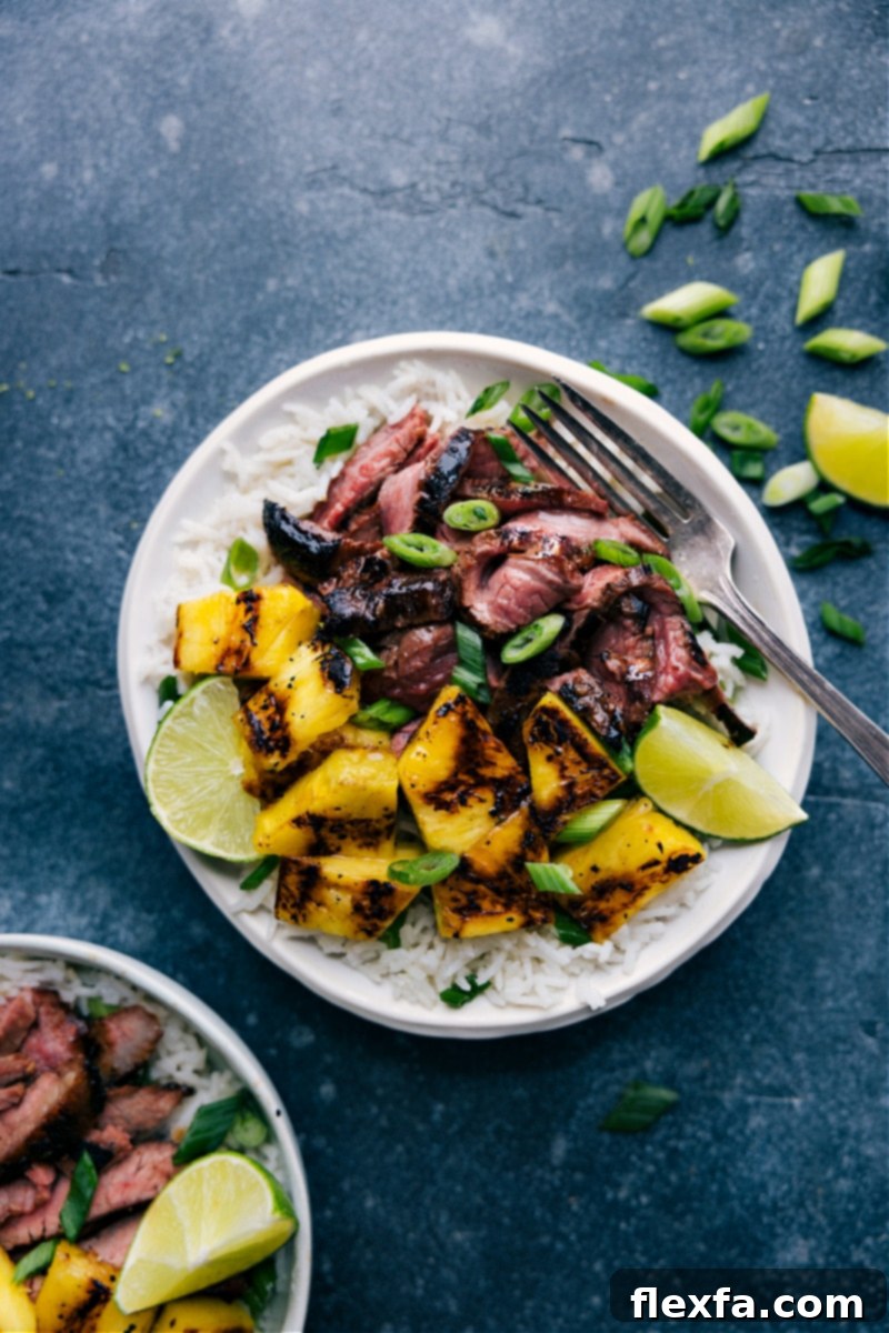 Overhead shot of a vibrant Pineapple Steak dish with perfectly grilled flank steak, caramelized pineapple slices, and fluffy coconut-lime rice, garnished with fresh green onions.