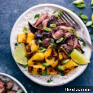 A close-up shot of the finished Grilled Pineapple Steak dish, highlighting the juicy, sliced flank steak, golden-brown grilled pineapple chunks, and fluffy coconut-lime rice. Perfect for a summer meal.