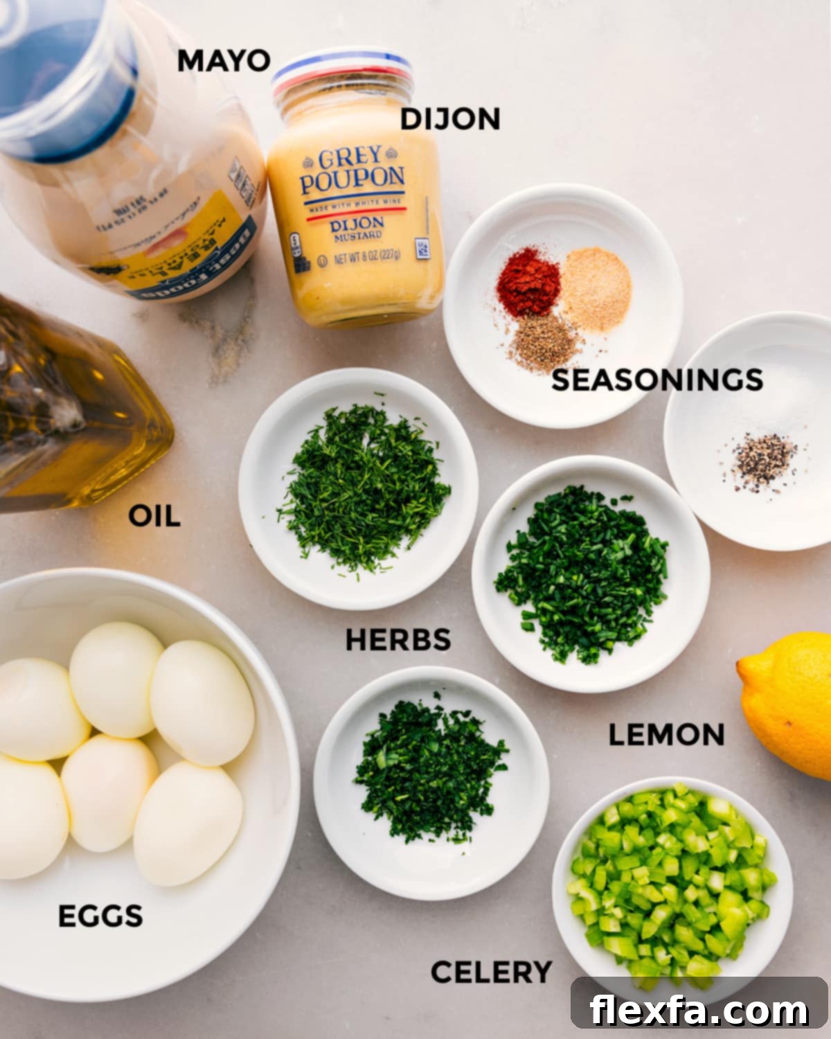 All the essential ingredients meticulously prepped for easy assembly of the best egg salad, including creamy mayo, zesty dijon, various seasonings, fresh herbs, a touch of olive oil, perfectly boiled eggs, bright lemon, and crisp celery.