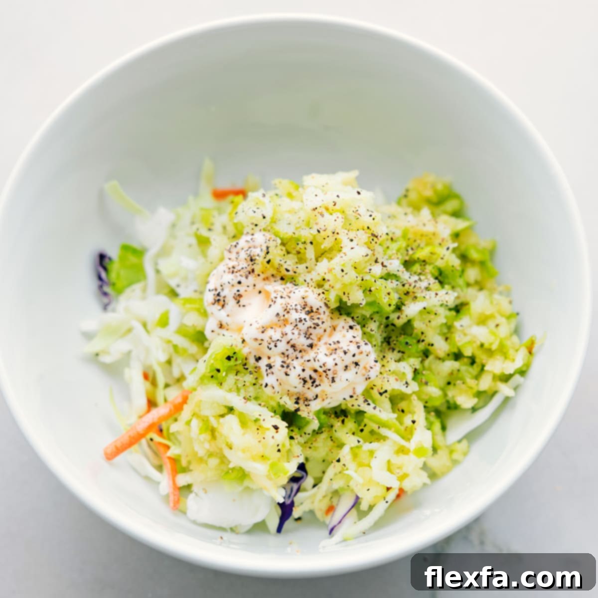 The coleslaw mix ingredients, including grated apple, being added to a large bowl for healthy turkey wraps.