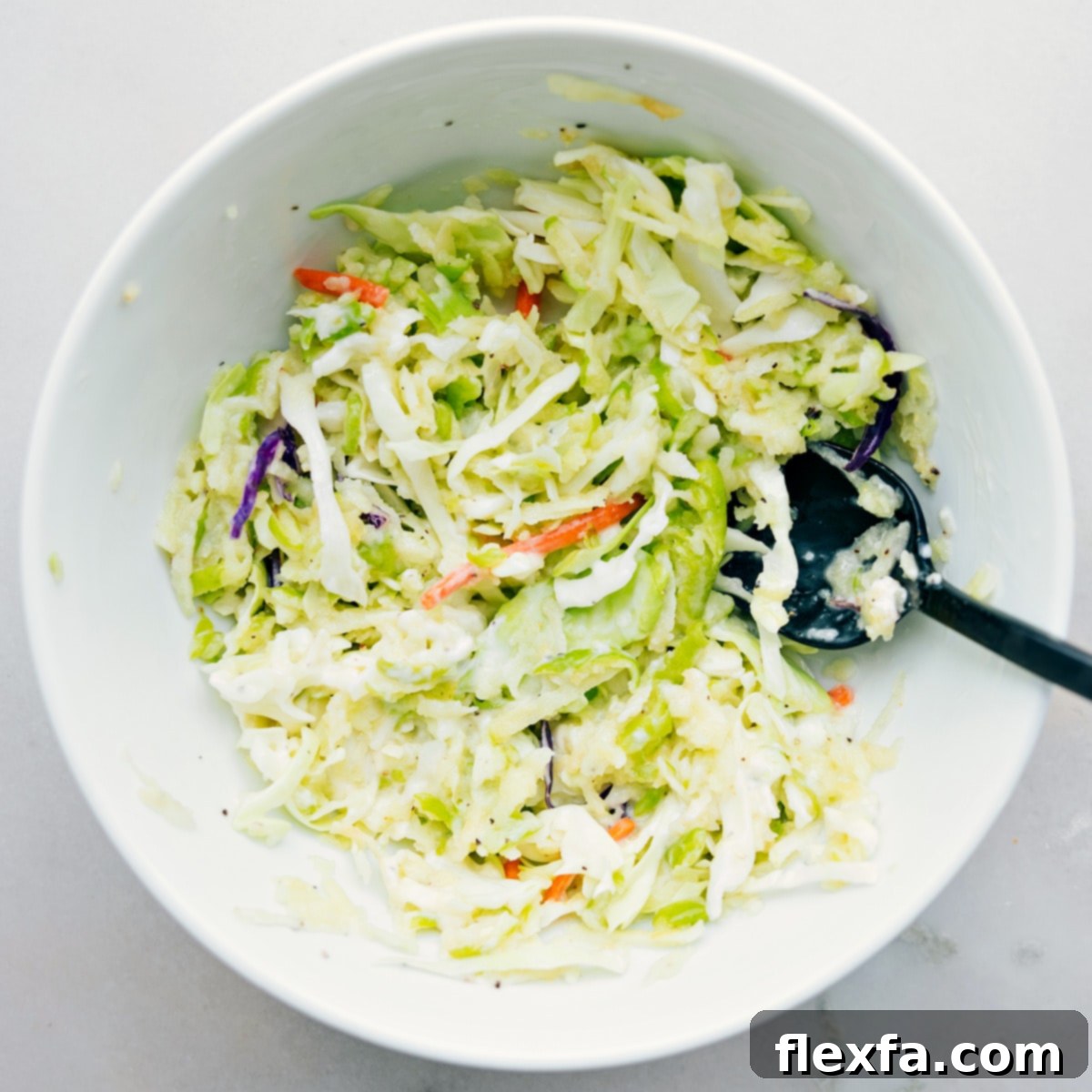 Mixing together the fresh coleslaw mixture in a large bowl, ready to fill healthy turkey wraps.
