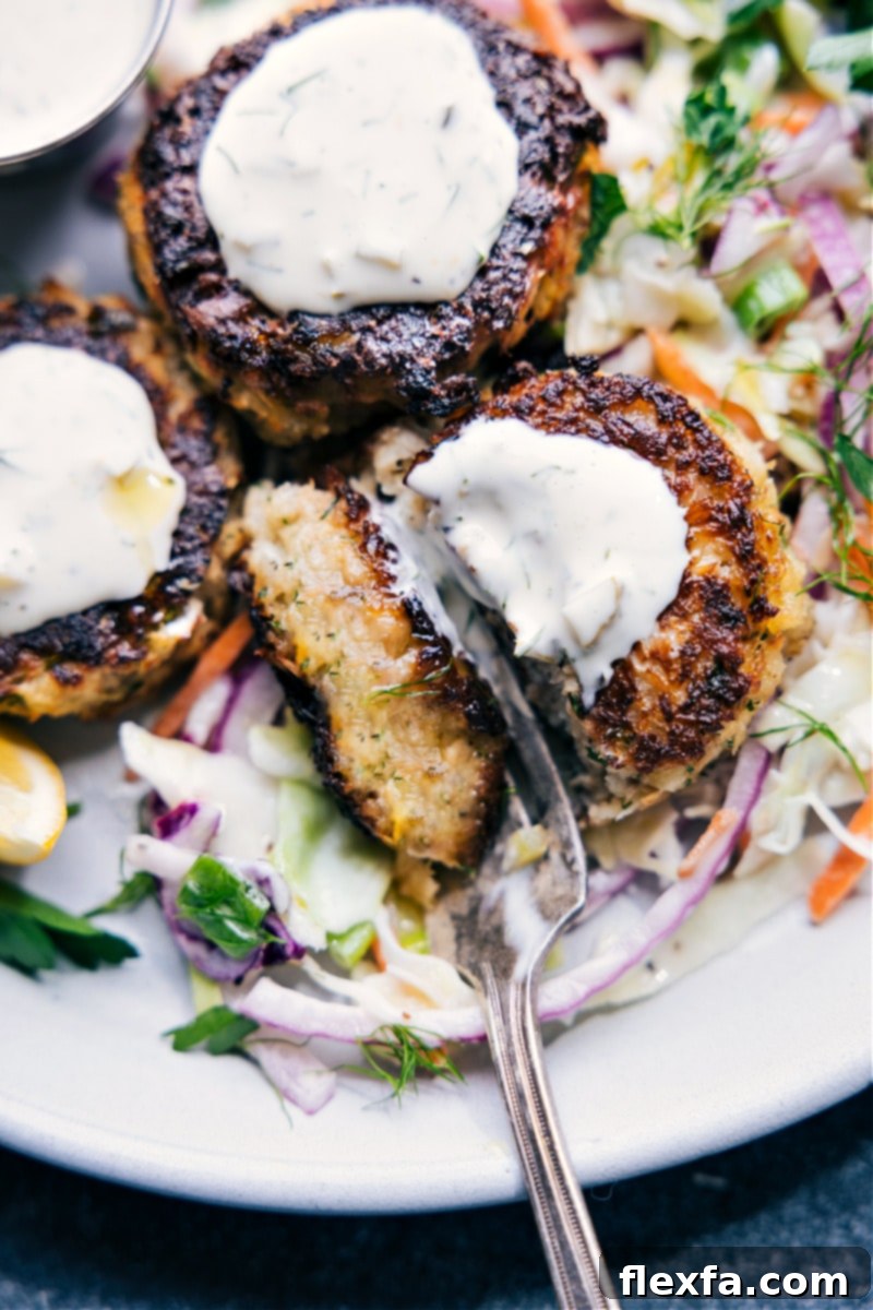 Crispy Tuna Cakes 8 Overhead shot of a full plate of tuna patties served on a bed of coleslaw, generously topped with tartar sauce and lemon wedges