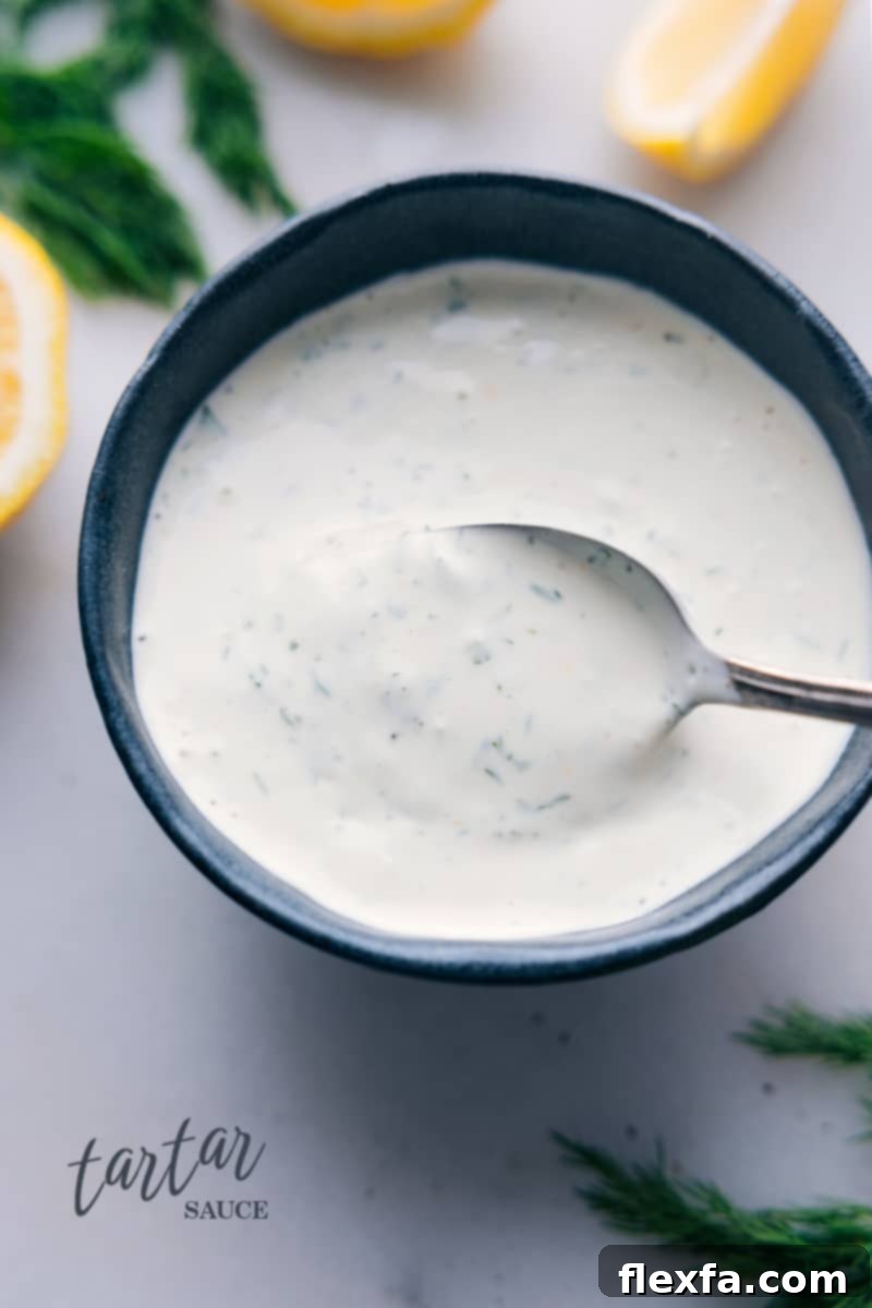 Elevate your seafood experience with this tangy, zesty, and fresh homemade Tartar Sauce recipe. Perfect for fish and chips, crab cakes, or salmon burgers. Quick, easy, and stores well in the fridge. Overhead image of a bowl of freshly made Tartar Sauce, garnished with fresh dill.
