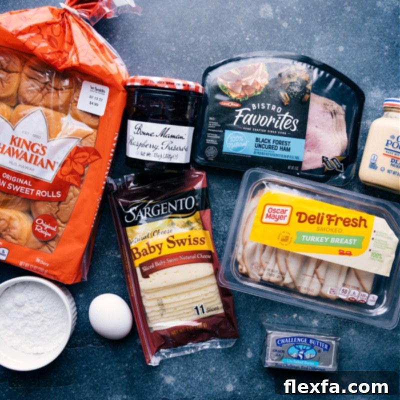 A vibrant display of all the fresh ingredients laid out for making Monte Cristo Sliders, including Hawaiian rolls, deli meats, cheese, mustard, and jam.