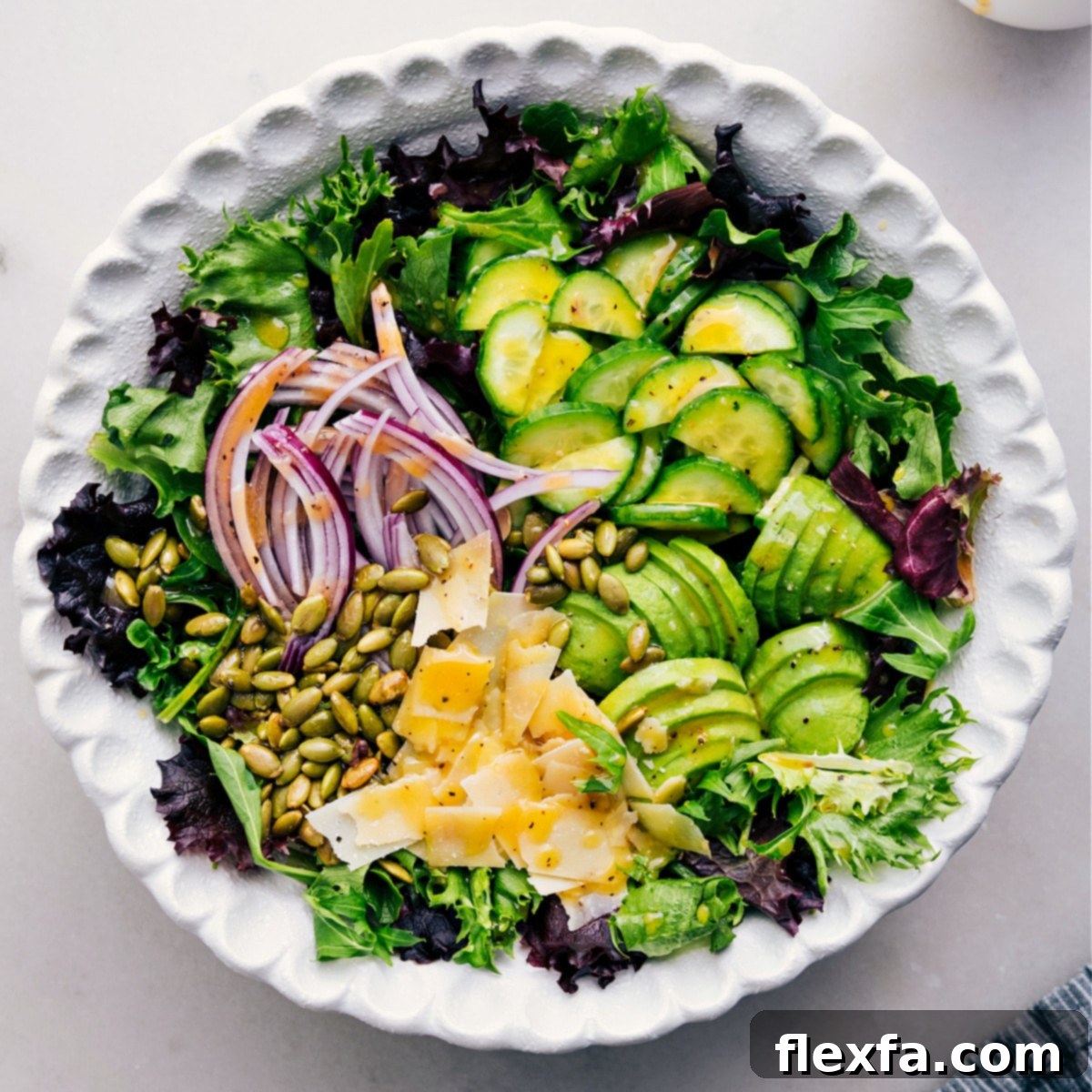 Expertly pouring the homemade dressing over a large bowl of freshly prepared Everyday Salad, ensuring every leaf and vegetable is lightly coated for maximum flavor.