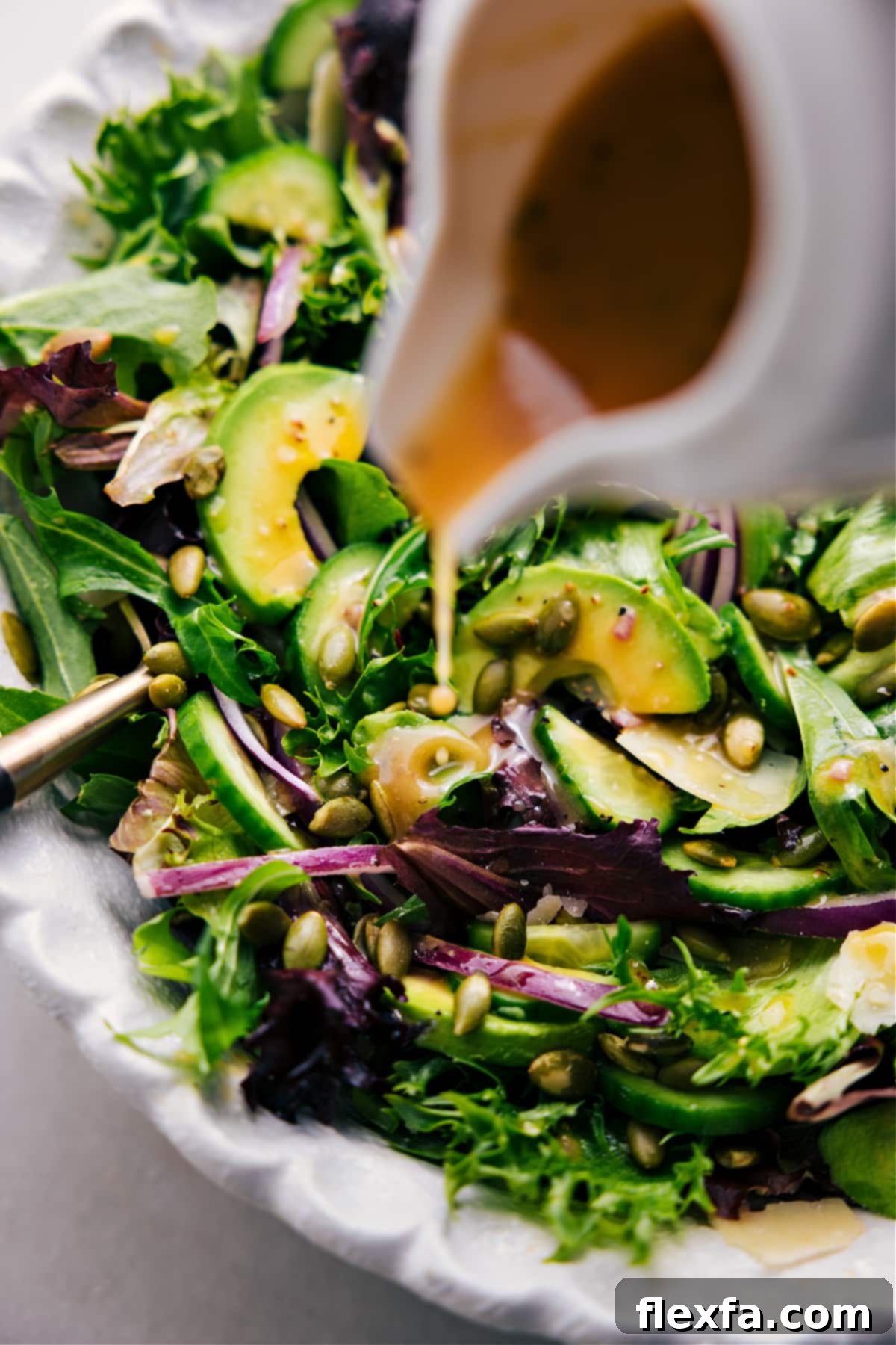 A close-up shot of the vibrant Everyday Salad being elegantly drizzled with its homemade dressing, highlighting the fresh ingredients and the rich texture of the vinaigrette.