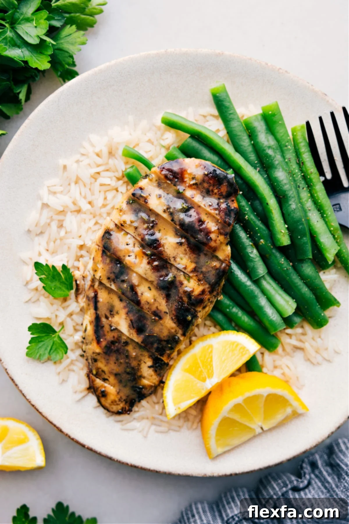 Italian Chicken Marinade recipe on a plate over a bed of rice with green beans. A vibrant and healthy meal.