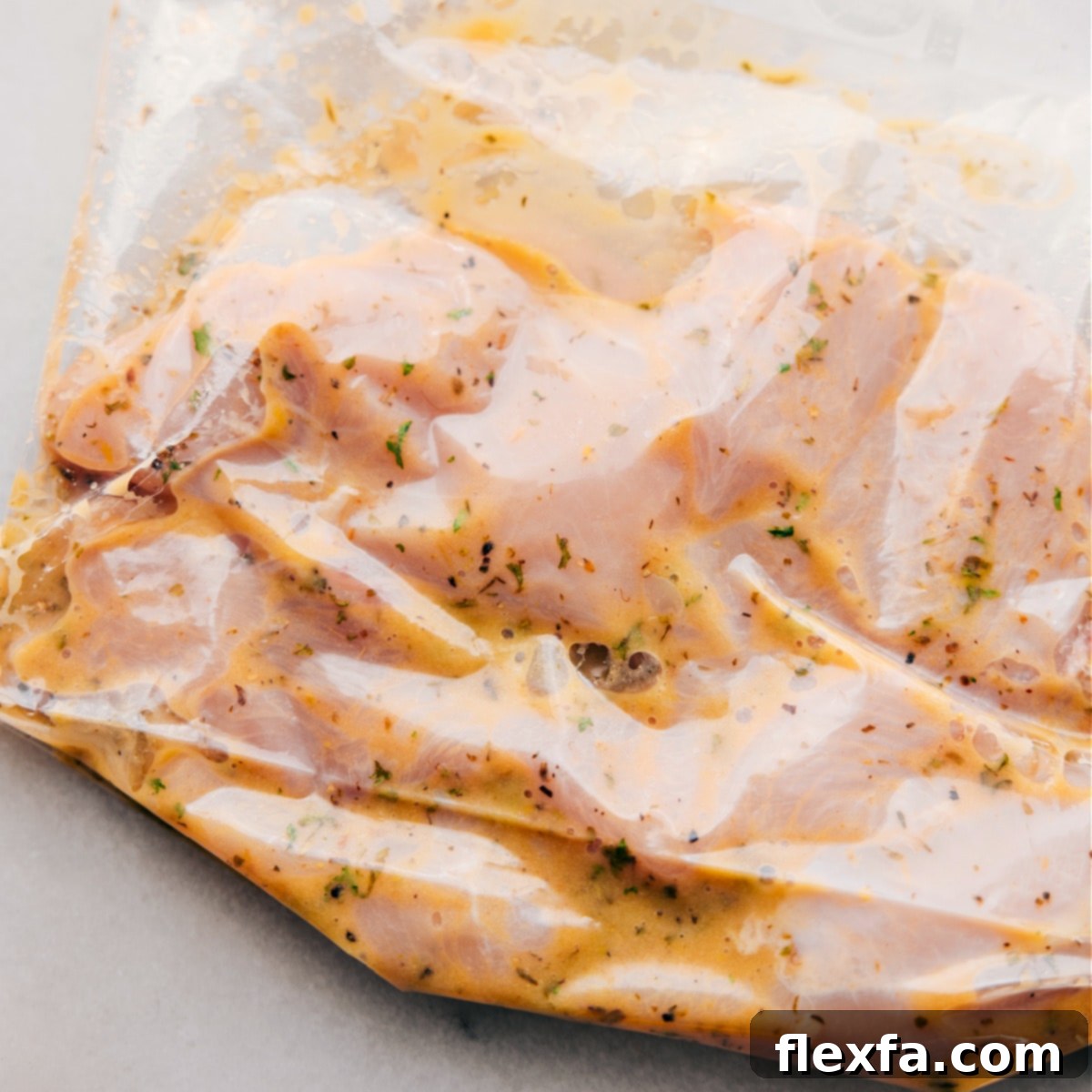 The chicken meat marinating in the Italian dressing in a freezer-size bag, ready for the fridge for flavor infusion.