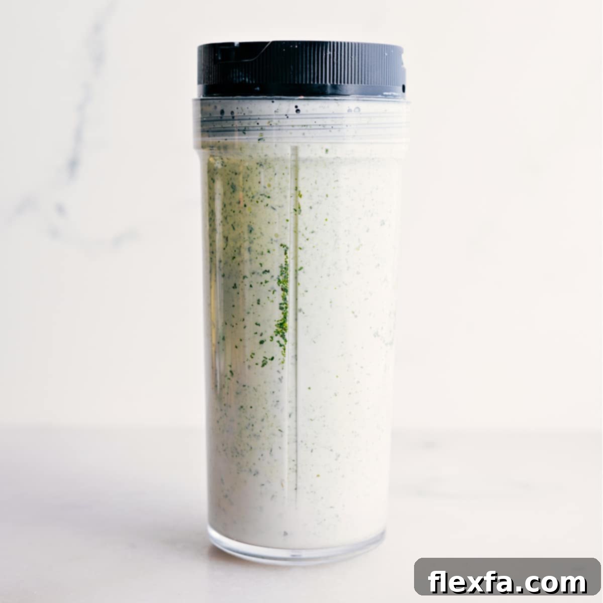 The vibrant green goddess dressing is smoothly blended in a blender jar, ready to be transferred.
