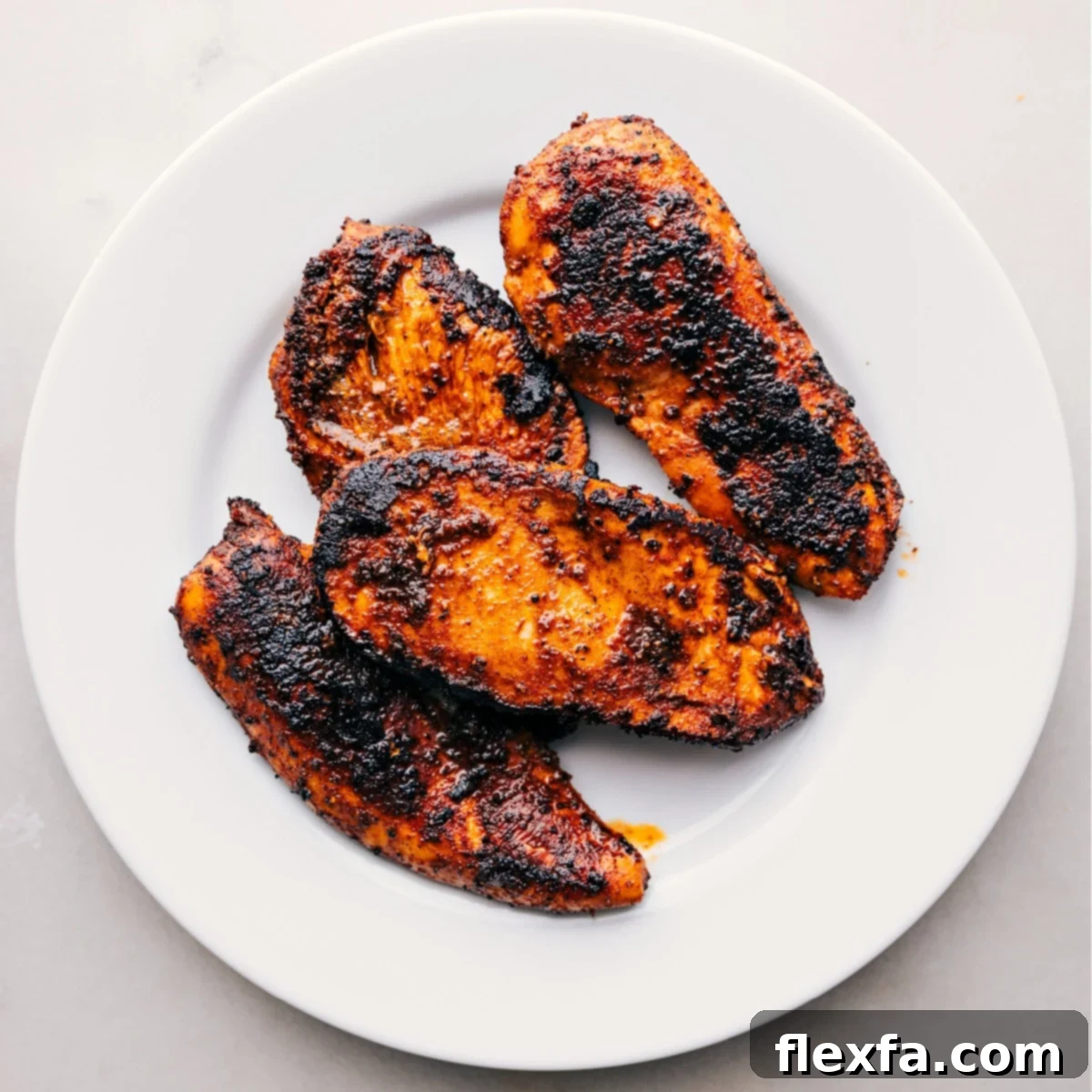 The perfectly cooked, simple blackened chicken recipe resting on a plate fresh out of the skillet to enhance flavor.