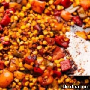 The roasted corn on a sheet pan fresh out of the oven, showing golden brown kernels and tender peppers.