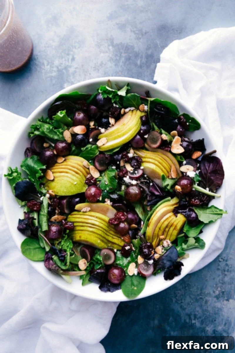 Vibrant pear, grape, and cherry green salad with a bowl of cherry balsamic dressing, ready to be served for a refreshing delight.