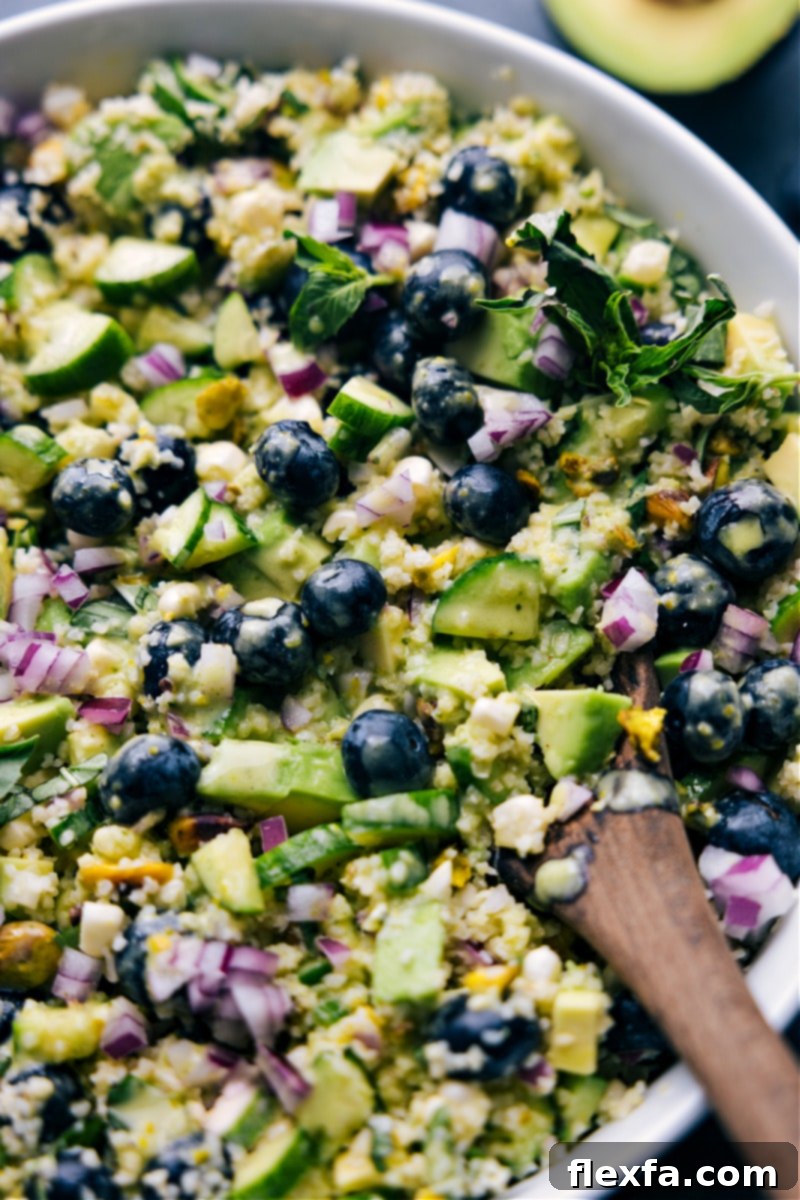This is our favorite Blueberry Corn Salad! Crisp corn, sweet blueberries, creamy avocado, crunchy pistachios, salty feta, and the BEST lemon-basil vinaigrette combine to create an unforgettable meal! Recipe via chelseasmessyapron #dinner #quick #easy #simple #lunch #best #familyfriendly #kidfriendly #blueberry #corn #salad Up-close overhead image of a bowl of Blueberry Corn Salad, beautifully garnished and ready to be served, highlighting its fresh and inviting appeal.