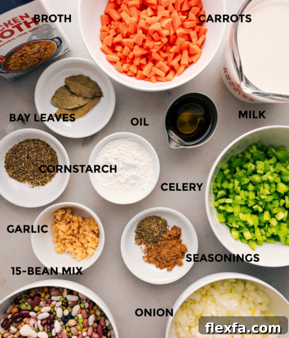 All essential ingredients for 15-Bean Soup prepped on a counter: fresh veggies, milk, bay leaves, dried beans, minced garlic, cornstarch, seasonings, and rich broth.