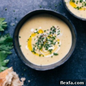 A bowl of creamy potato leek soup garnished with fresh herbs.