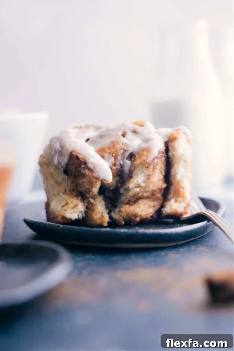Enjoying the best easy cinnamon roll recipe – a close-up of a perfectly baked, frosted cinnamon roll.