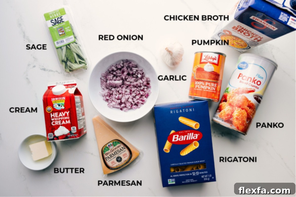 All the essential ingredients for preparing a delicious pumpkin pasta, including fresh sage, unsalted butter, heavy cream, freshly grated parmesan, red onion, minced garlic, rigatoni pasta, panko breadcrumbs, 100% pure canned pumpkin purée, and chicken broth, neatly arranged on a wooden surface.