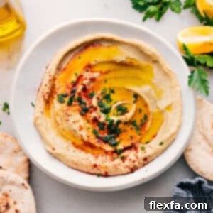 A serving of finished creamy hummus in a bowl, topped with a swirl of olive oil and a sprinkle of paprika.