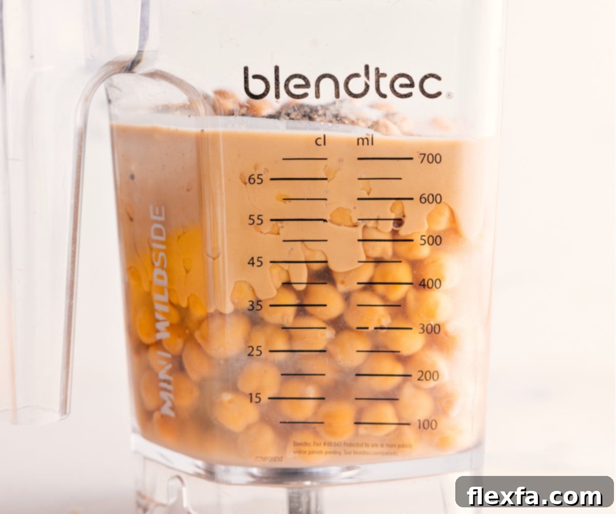 All the prepped ingredients for hummus are carefully placed into a high-speed blender, positioned to be transformed into a perfectly smooth and creamy dip.