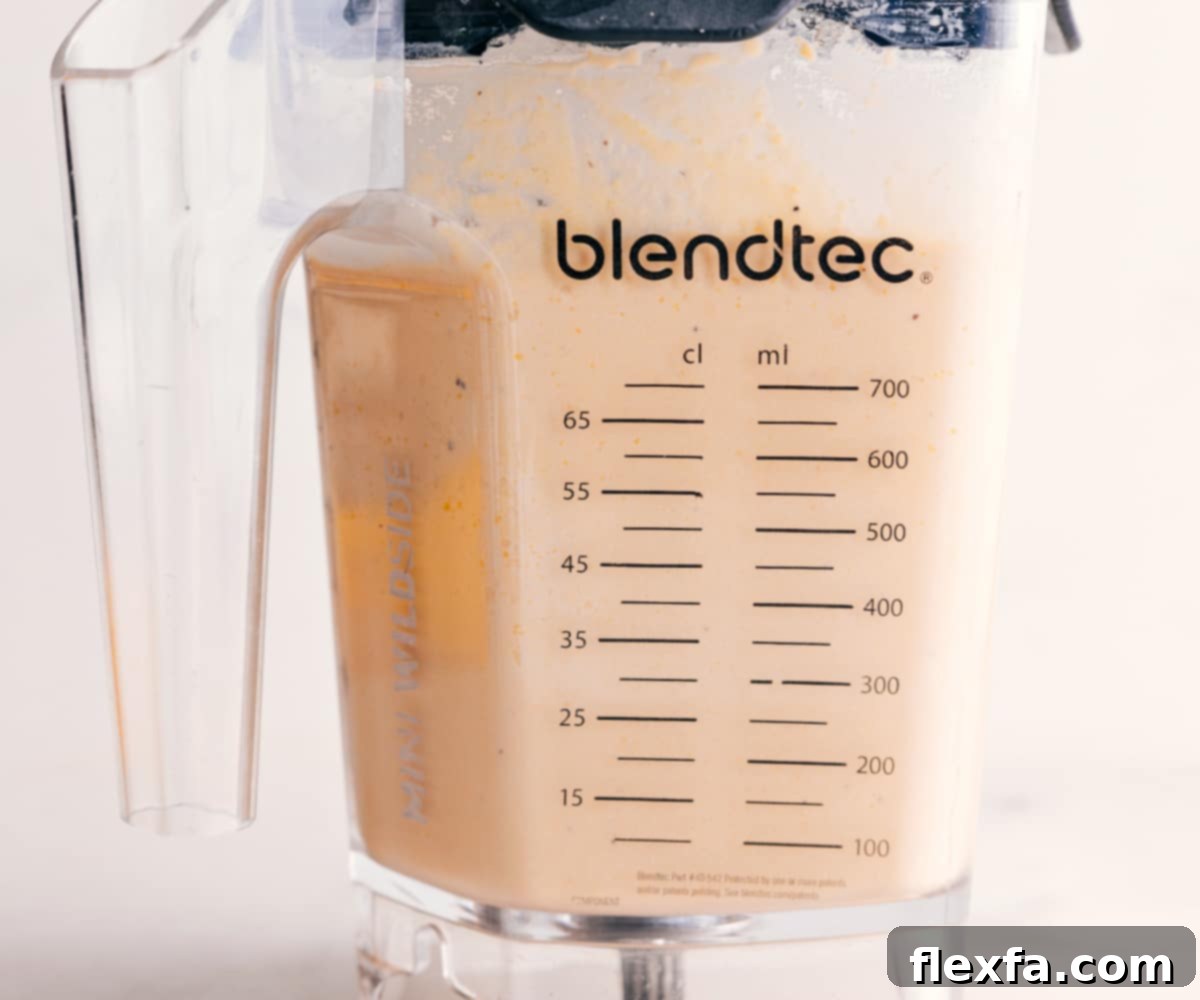 The hummus mixture inside the blender has achieved a perfectly smooth and ideal creamy consistency, signifying it's ready to be served as an exquisite dipping sauce.