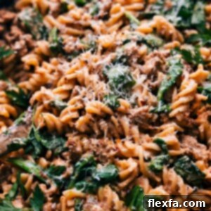 Close-up of a bowl of creamy Italian sausage pasta, showcasing the rich sauce, tender pasta, and bits of sausage and spinach.