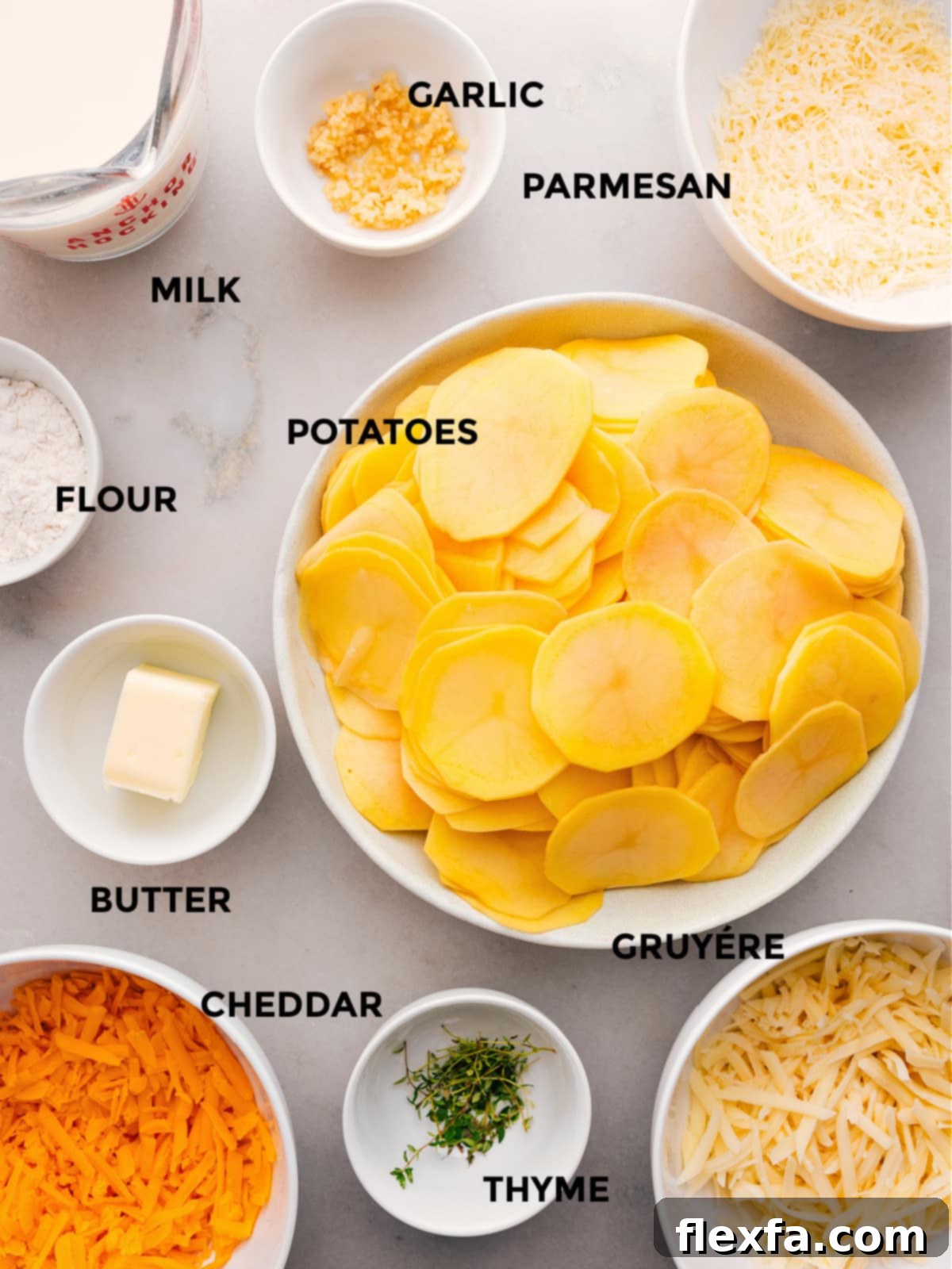 Essential ingredients for Au Gratin Potatoes: potatoes, flour, butter, thyme, a blend of cheeses, milk, and fresh garlic.